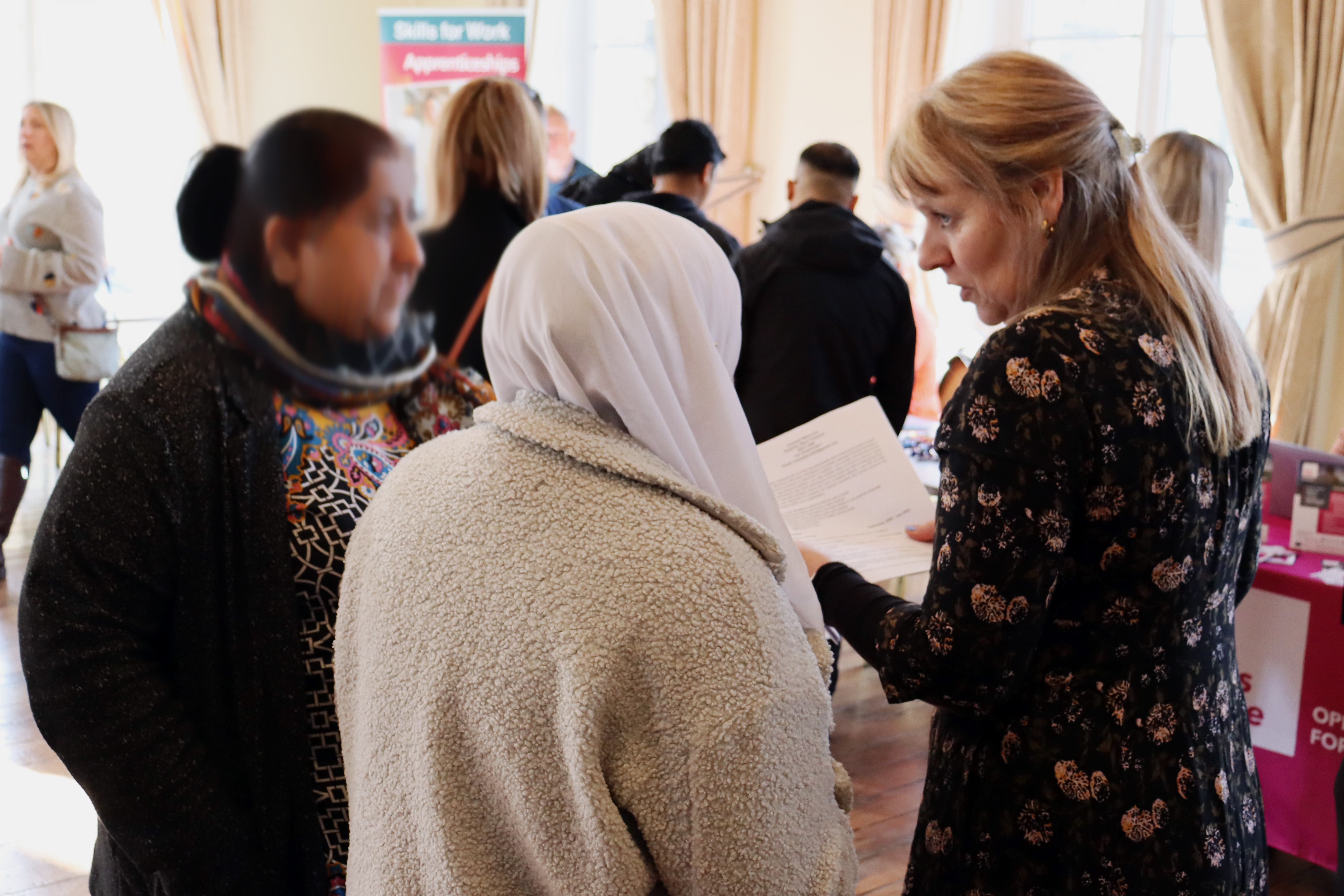 A woman holding some papers talking to two other women