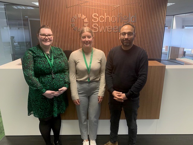 Three people in front of a reception desk