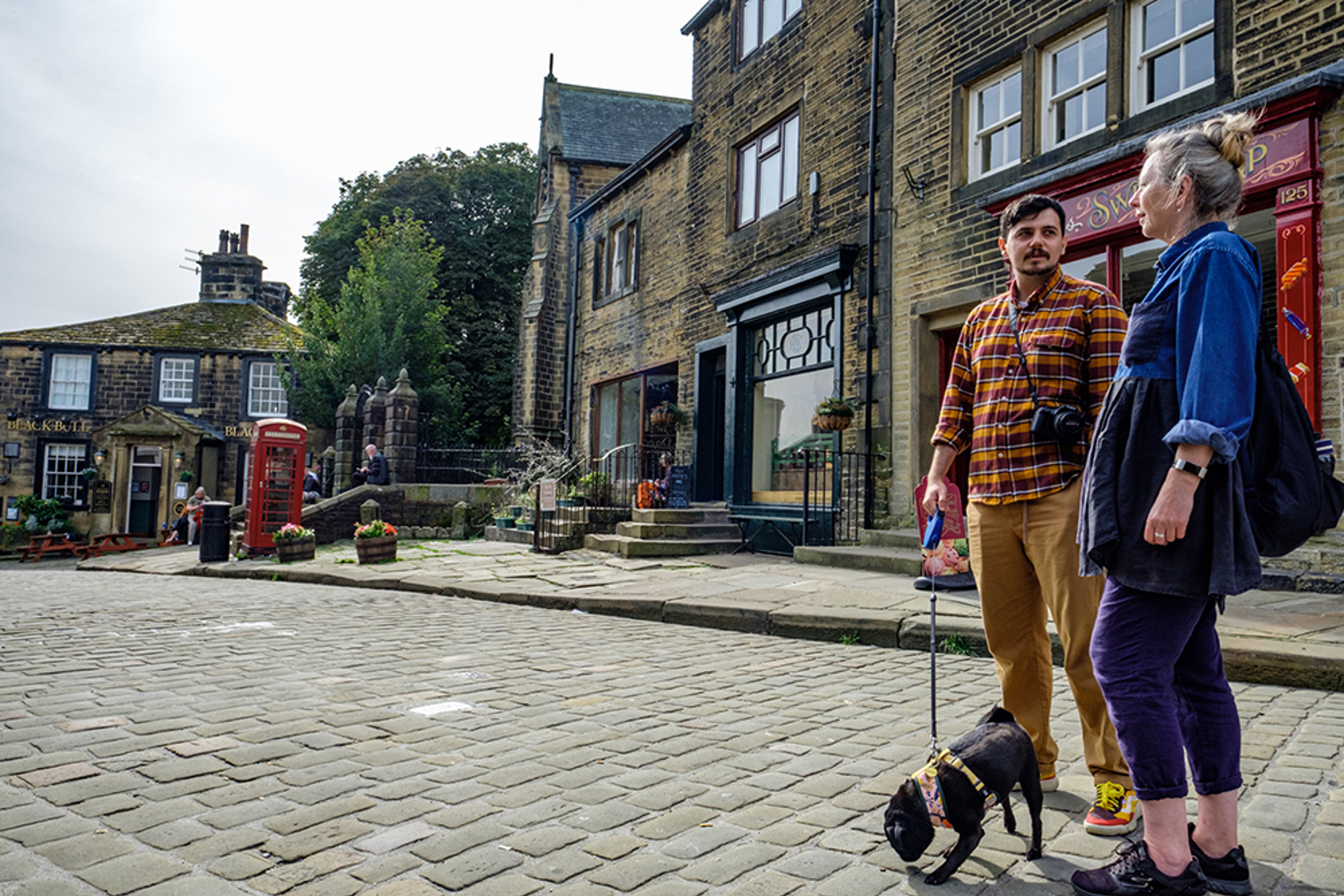 Man, woman and dog on the cobbled streets of Haworth