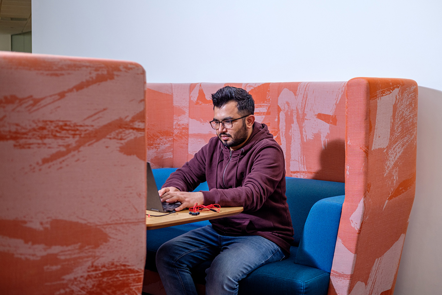 Man sat in a booth working at a laptop