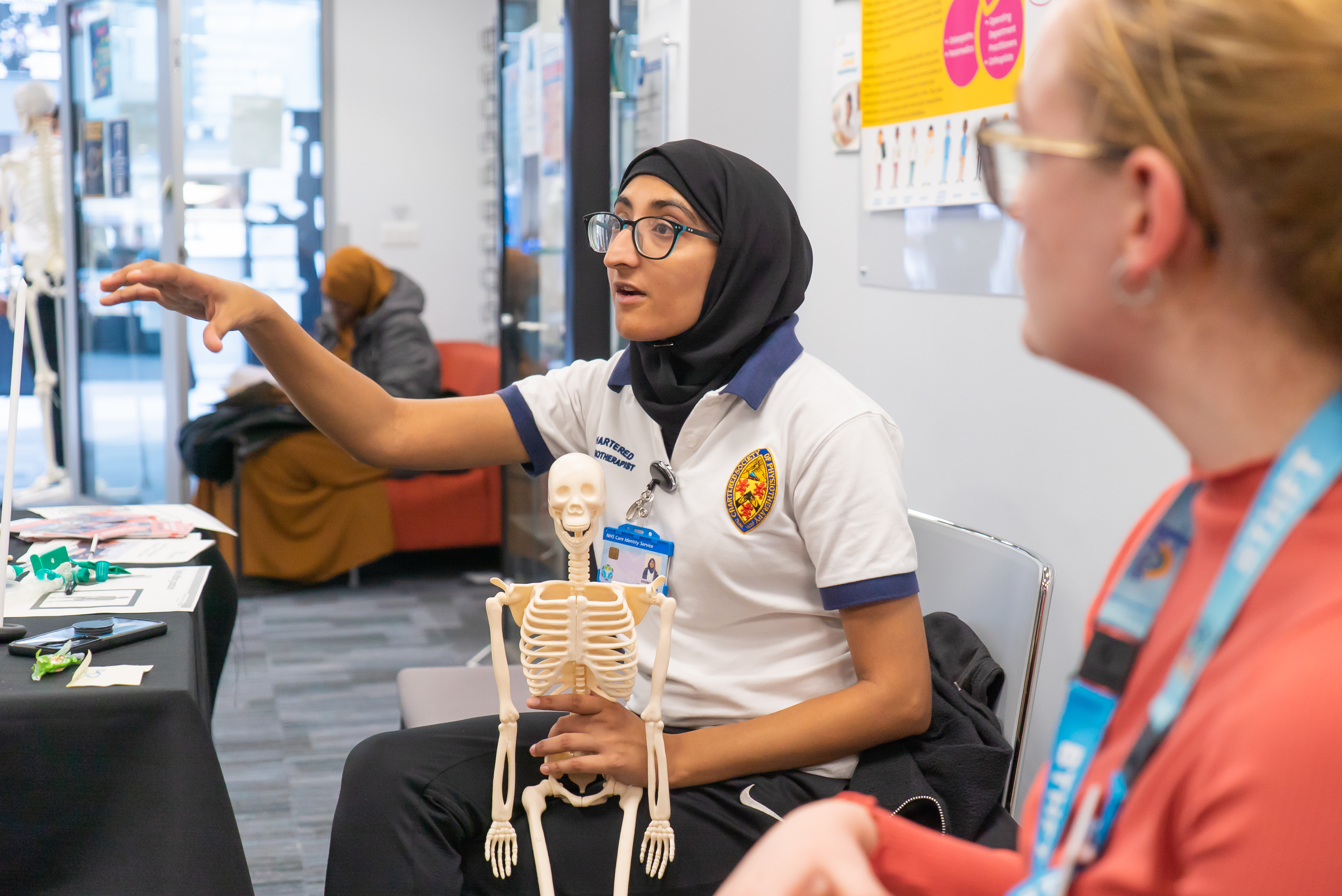 Woman in healthcare uniform sat holding small skeleton