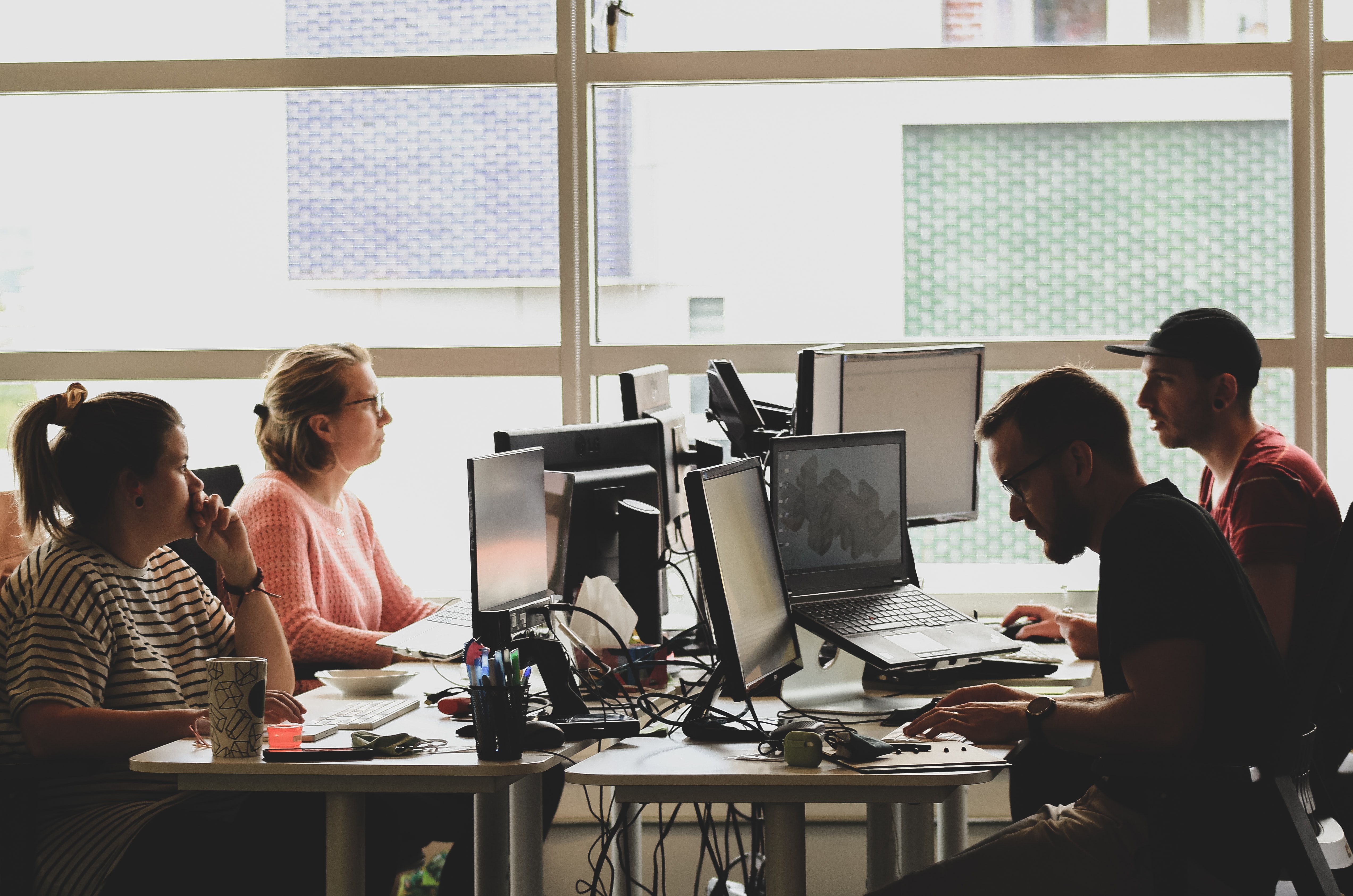 A group of four people sat at desks working on computers