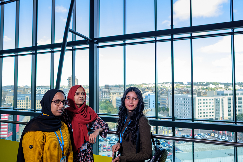 Three young women stood in front of a large window