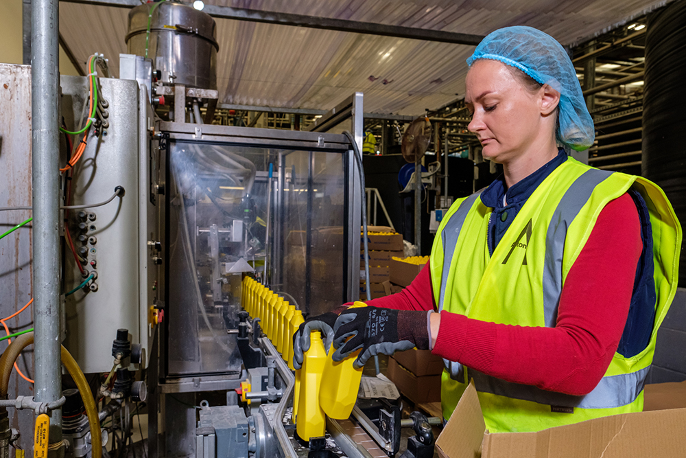 A woman in protective clothing working at a factory production line