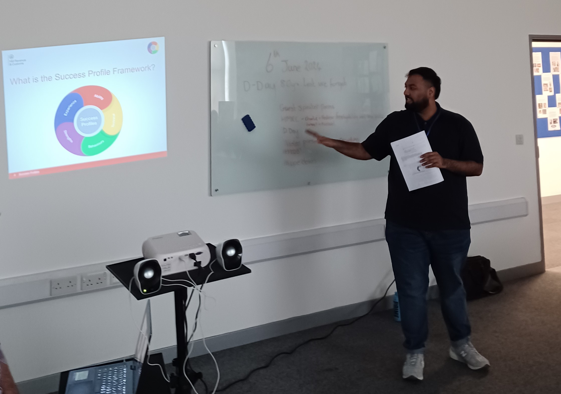 A man giving a presentation using a whiteboard and image projector