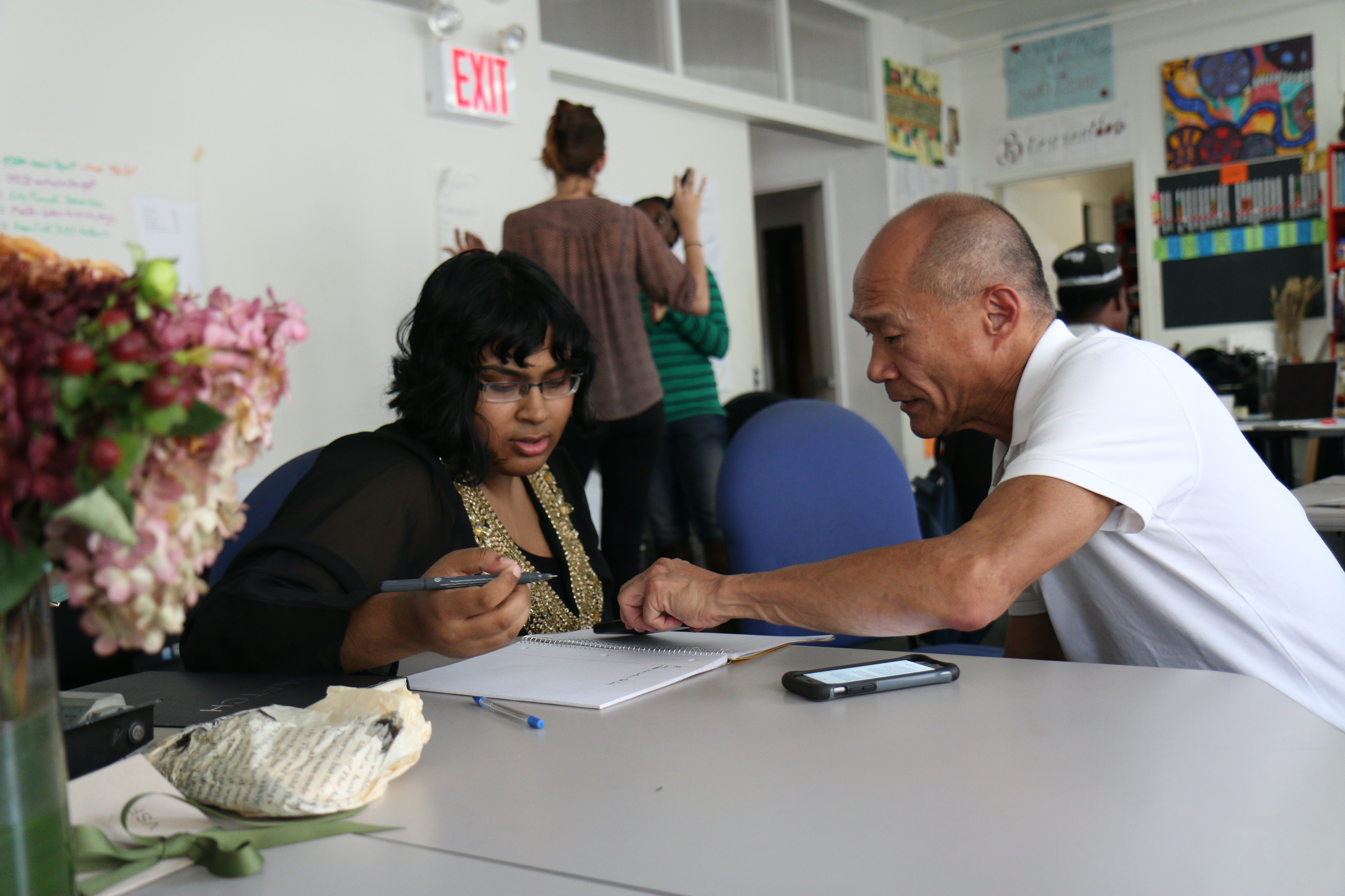 A man showing something in a book to a woman