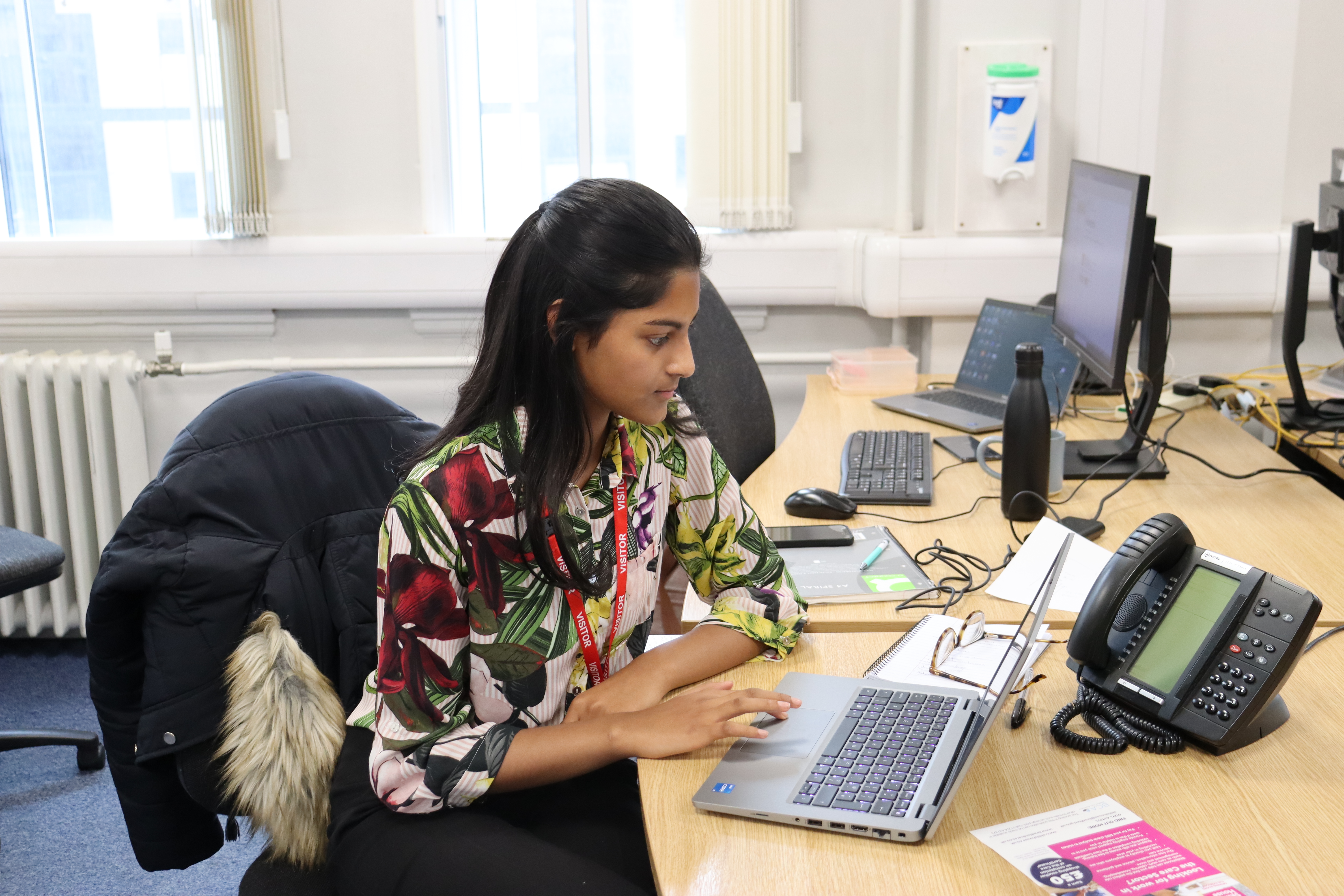 A girl working at a desk with laptop and telephone