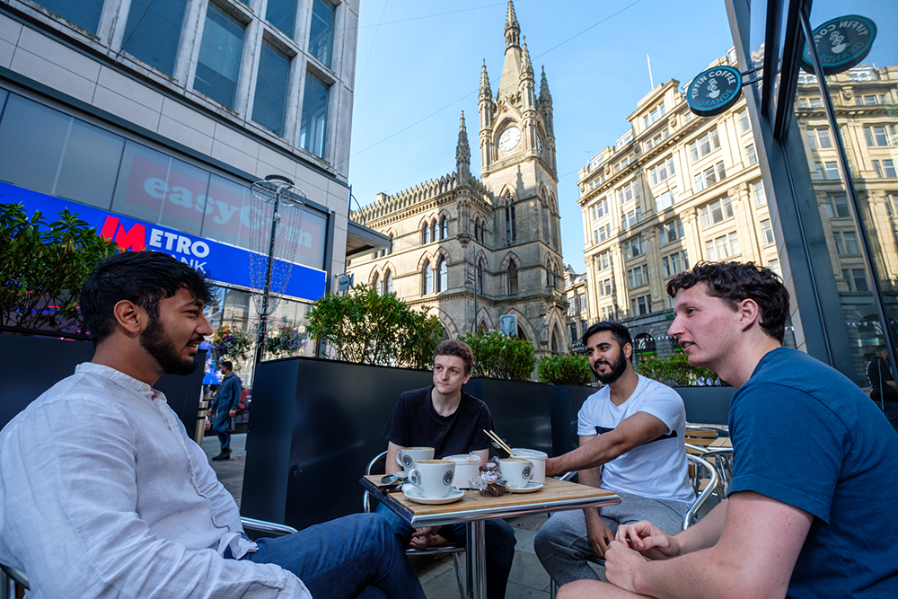 A group of young men sat at an outdoor cafe table in Bradford centre