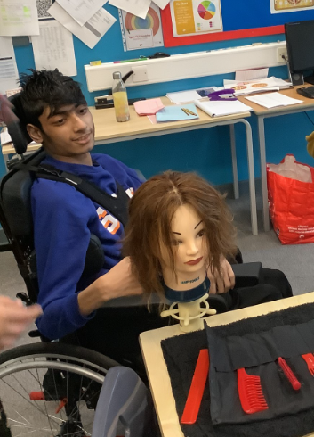 A young man in a wheelchair working with a mannequin head