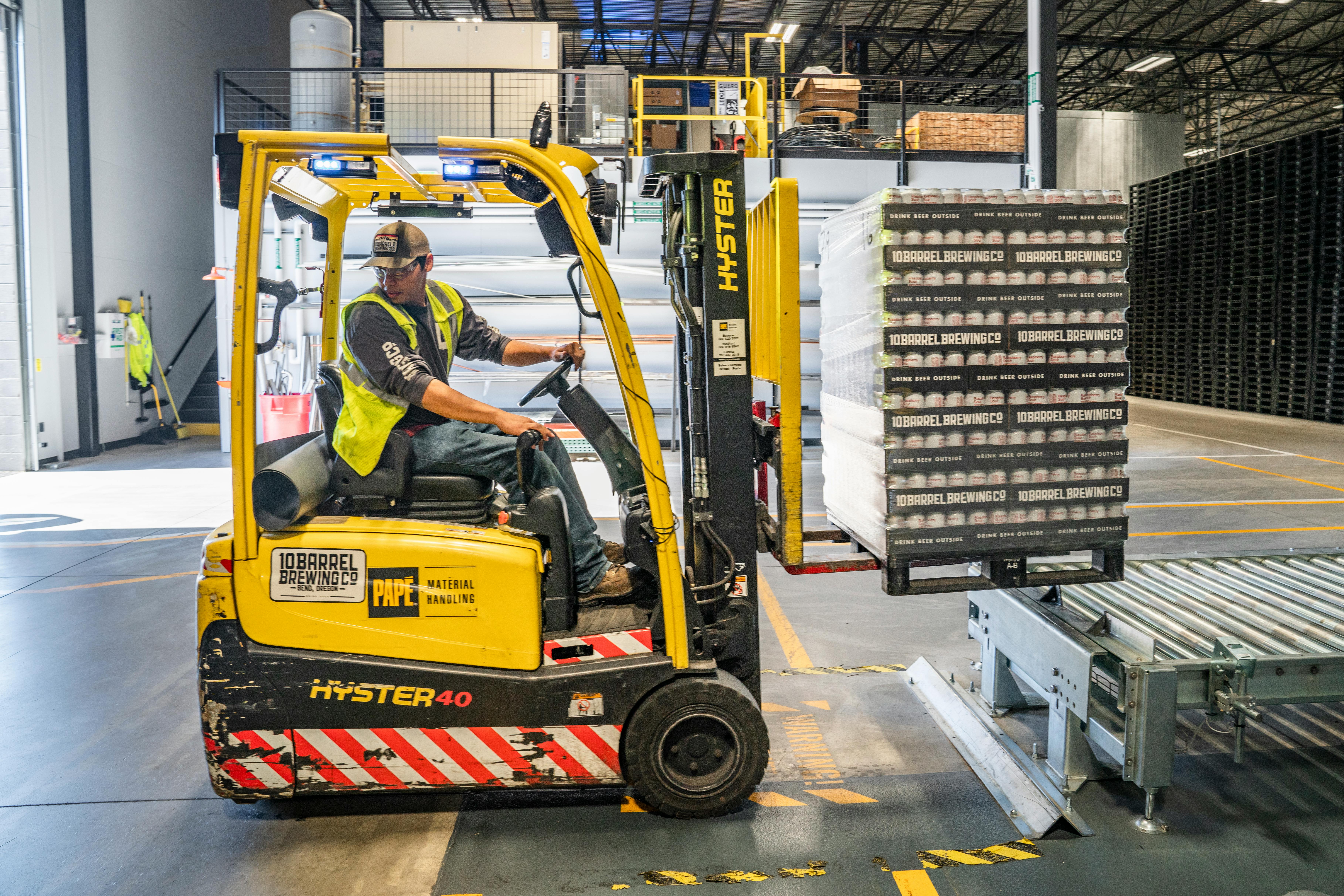 A man driving a fork lift truck with a full load on the front