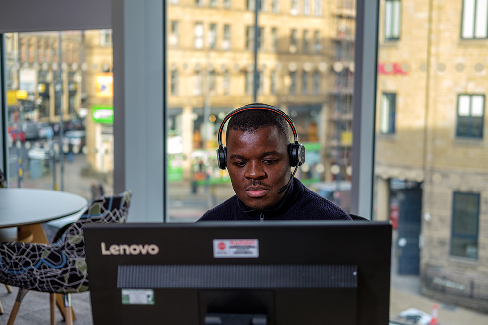 A man sits at a computer with headphones on