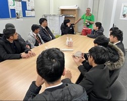 Young people sat around a boardroom table watching a presentation