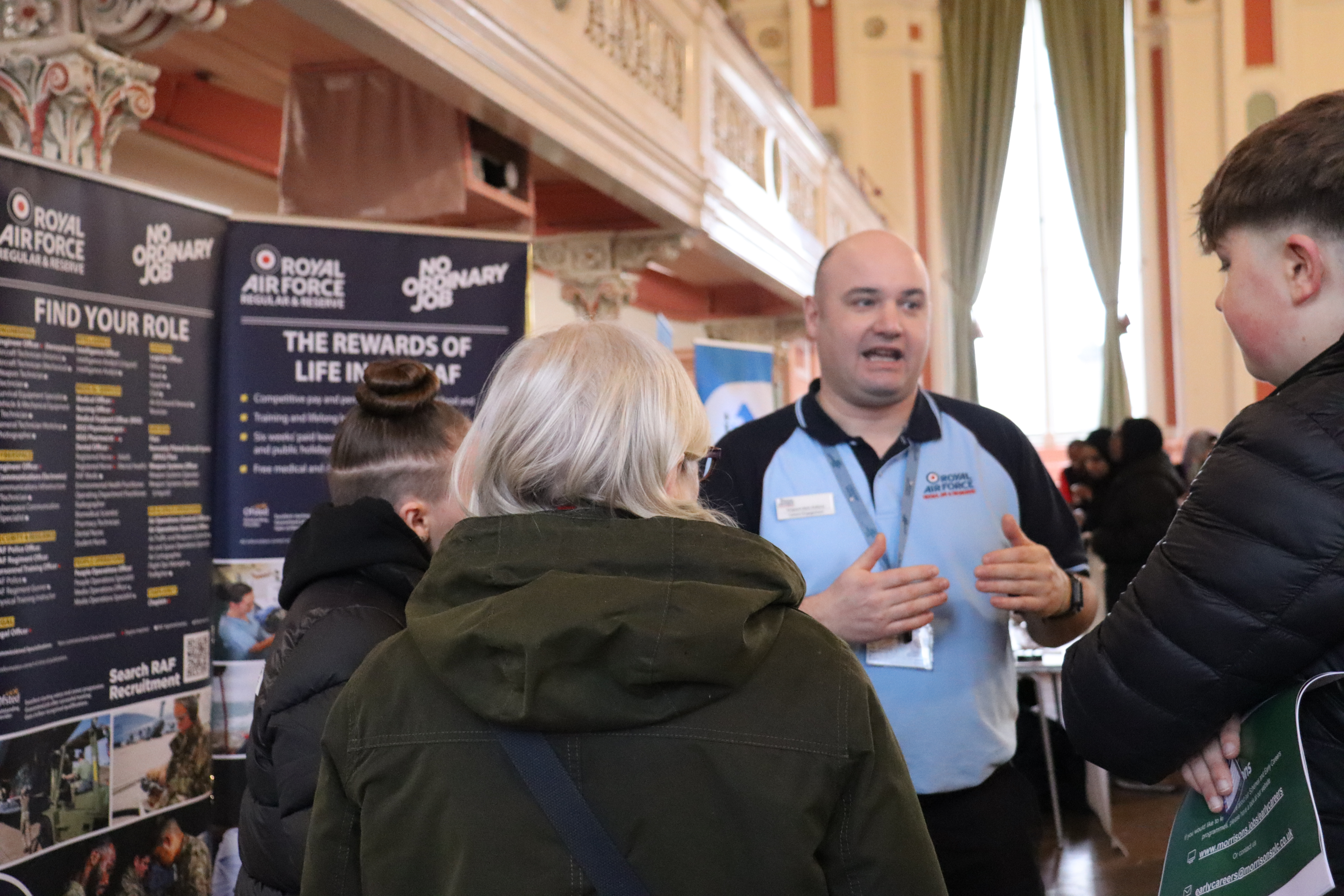 A man in a Royal Air Force top talking to a group of young people