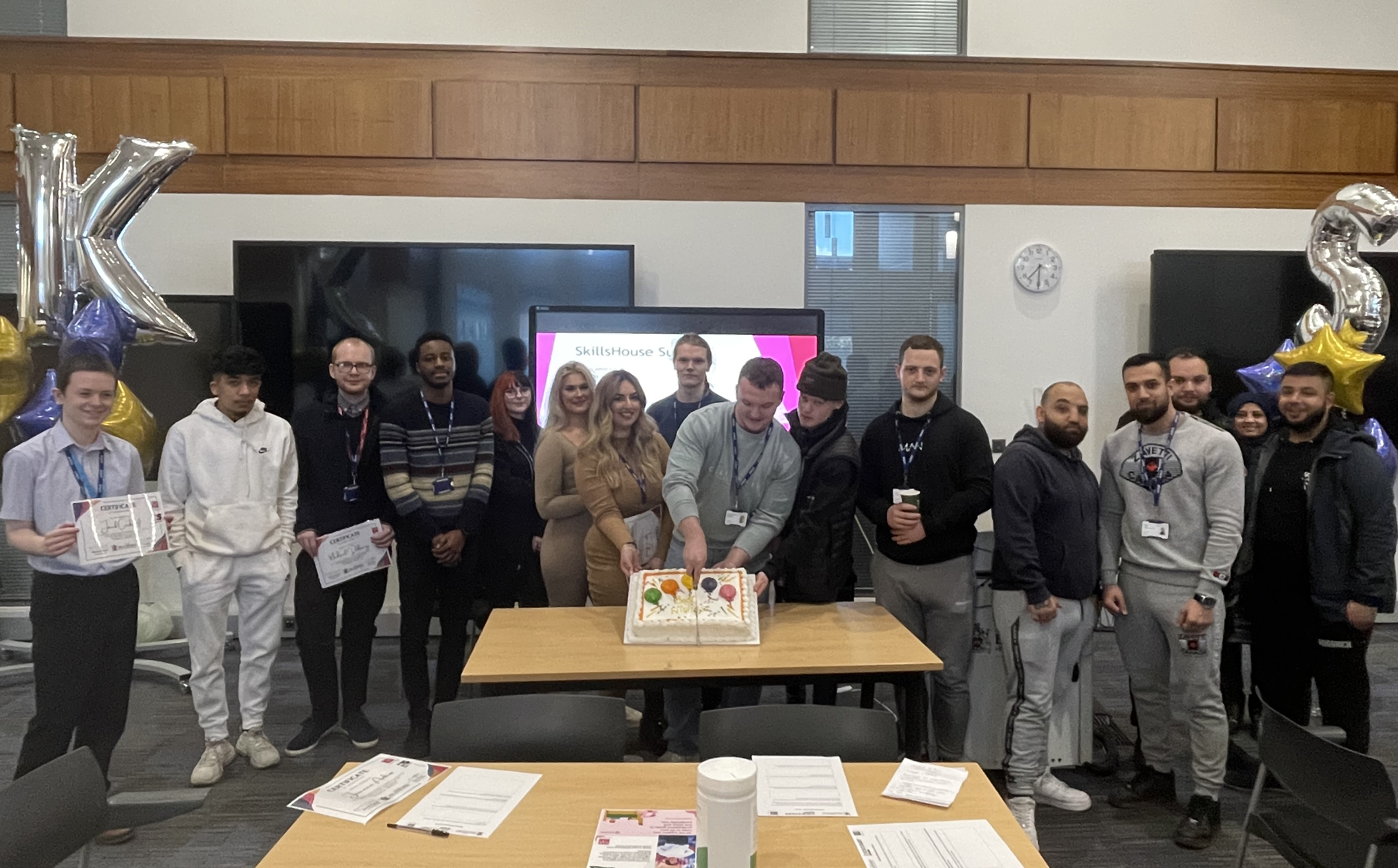A group of young people, one is cutting a celebration cake