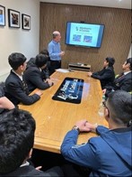 Young people sat around a boardroom table watching a presentation