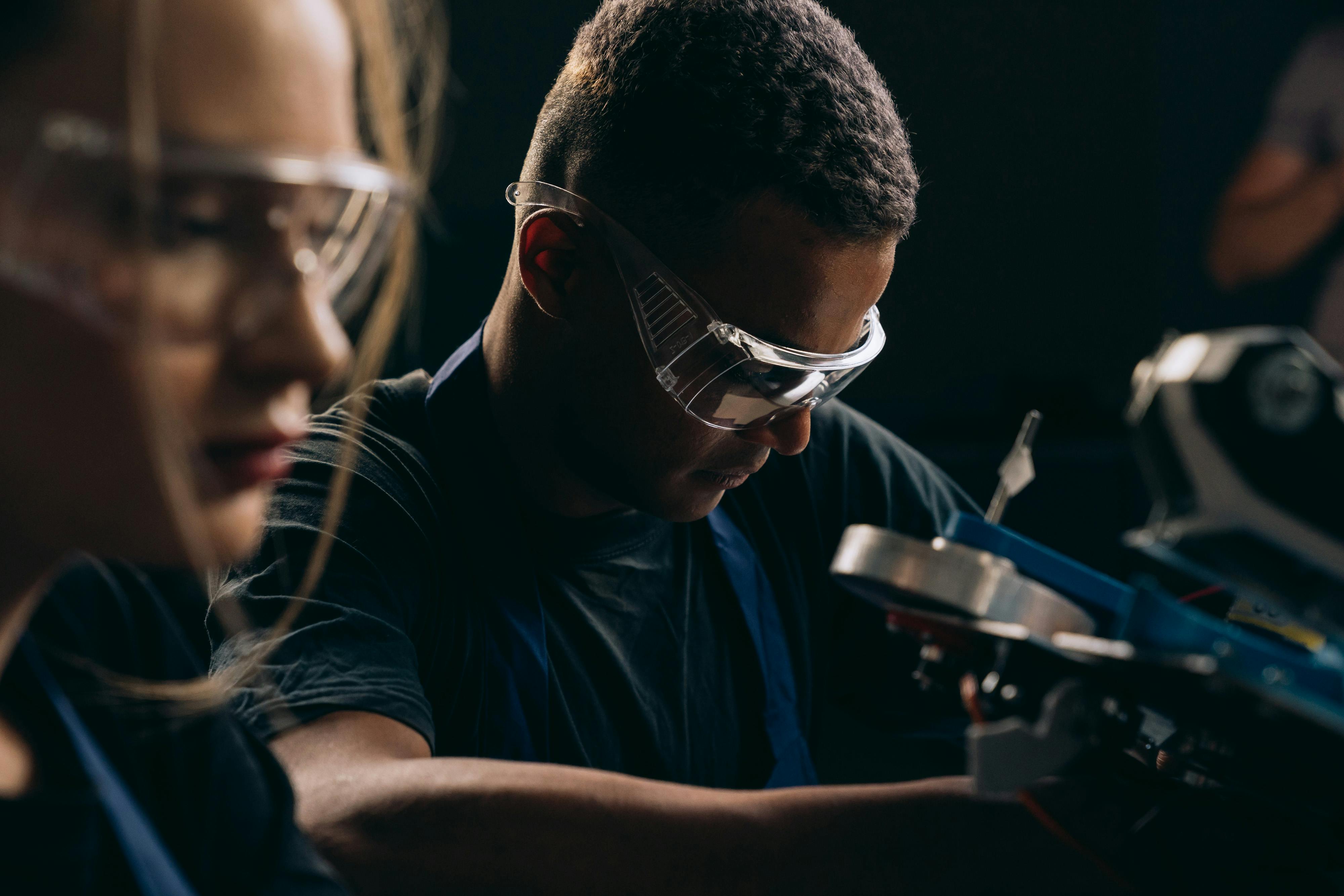 Two people in safety goggles using some equipment