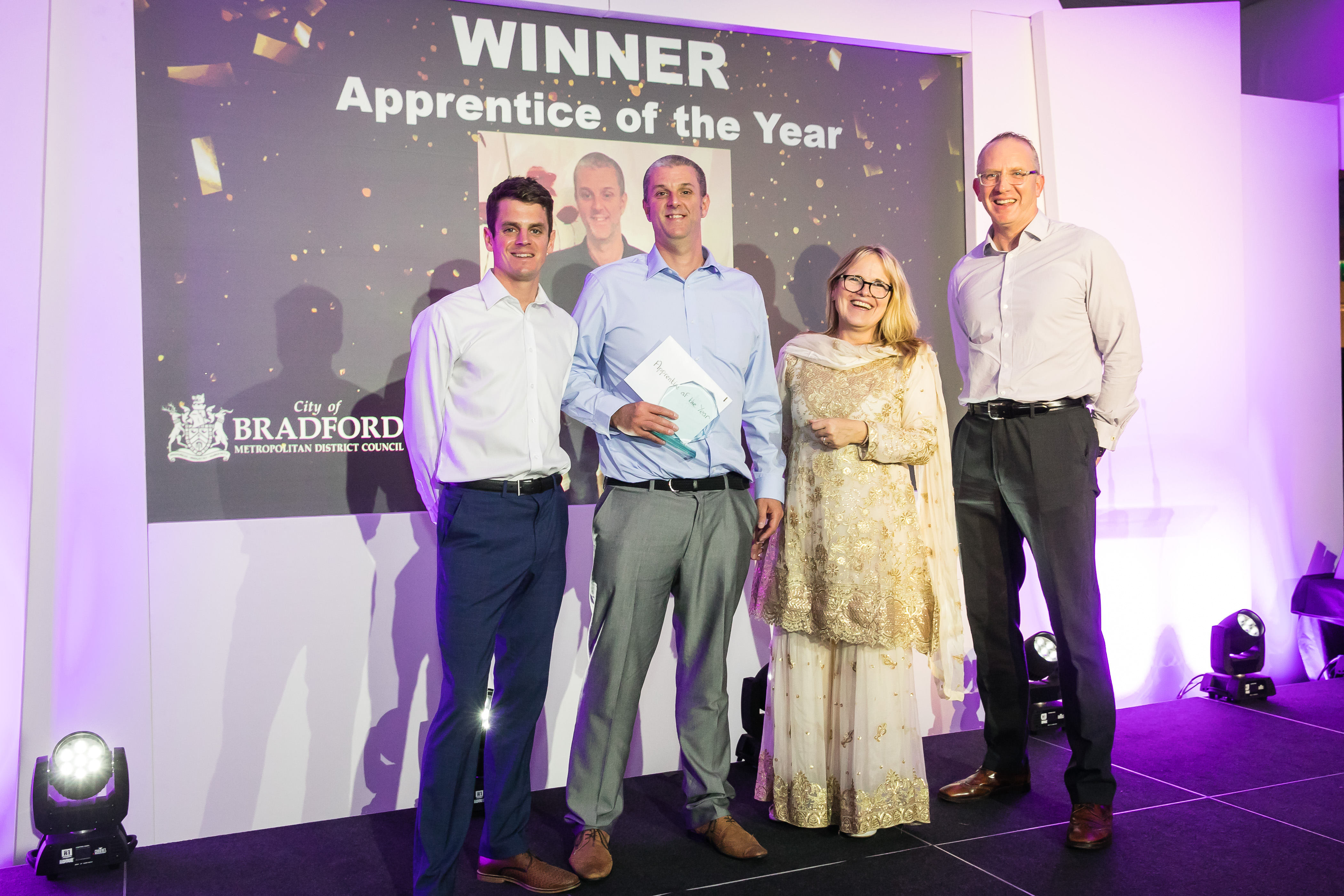 Four people stood in front of a presentation screen saying Apprentice of the Year