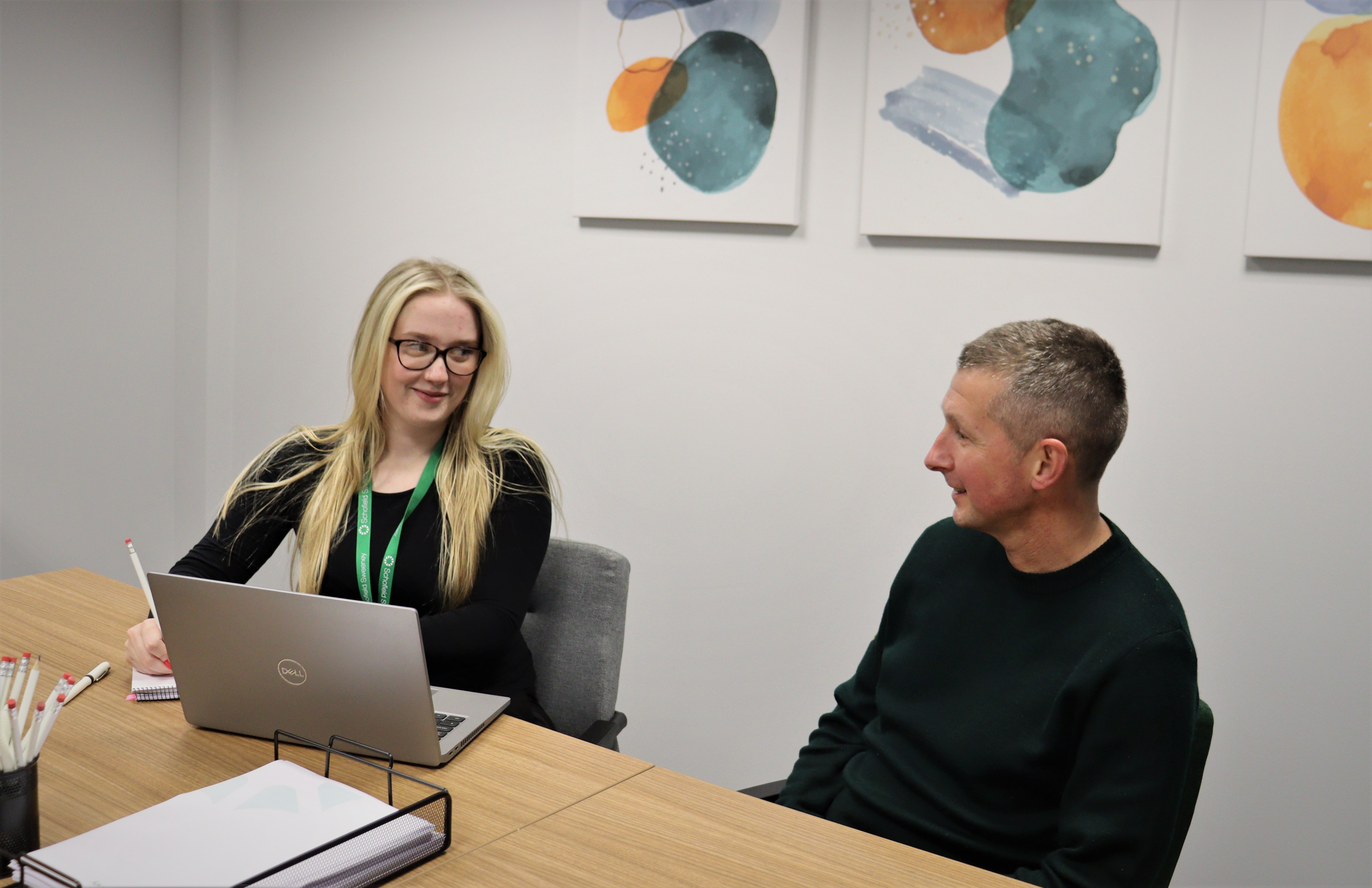 A young woman on a laptop talking to a man