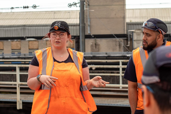 A young woman wearing high vis talking to other people