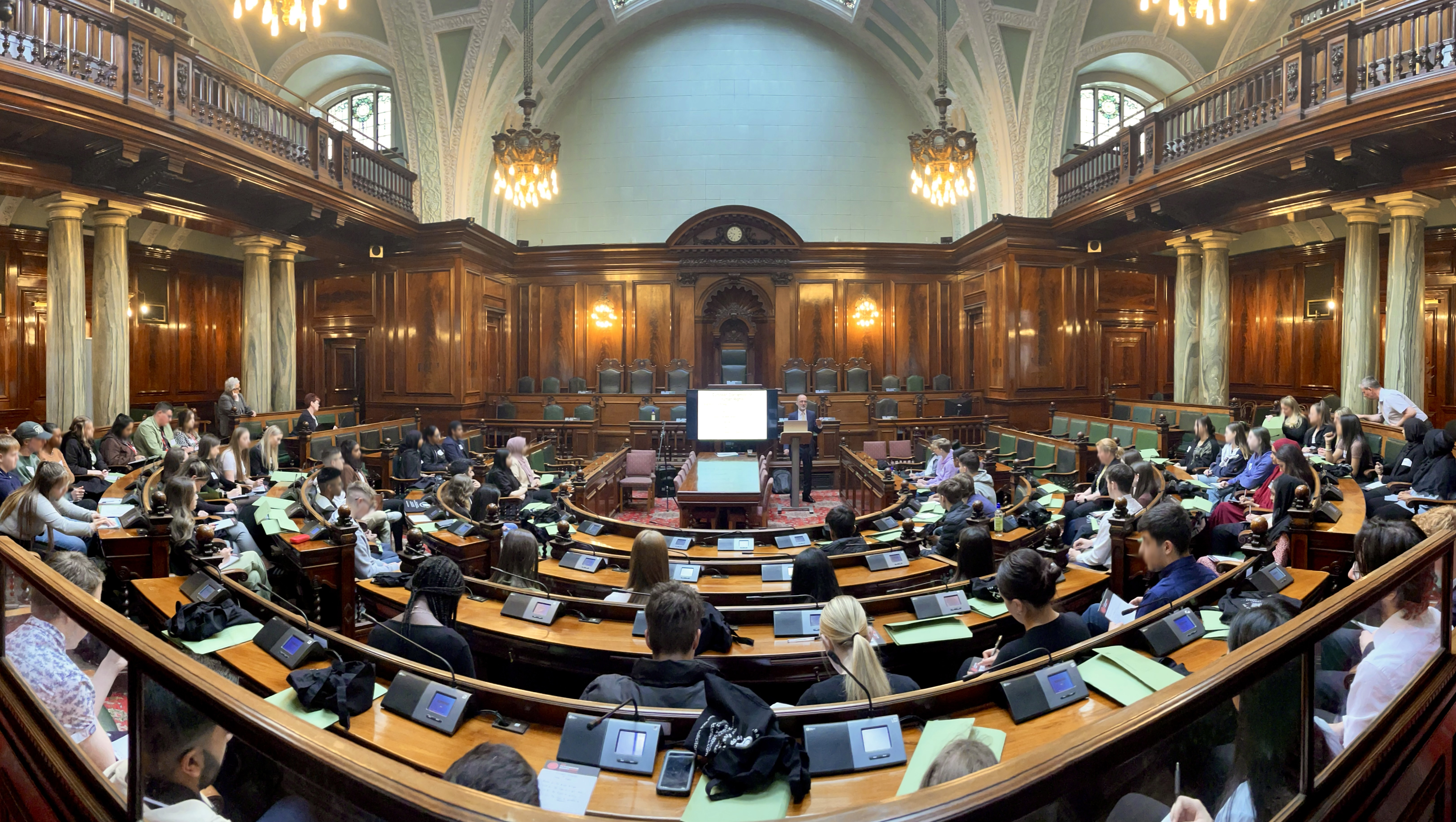 A group of young people in a courtroom watching a man give a presentation at the front