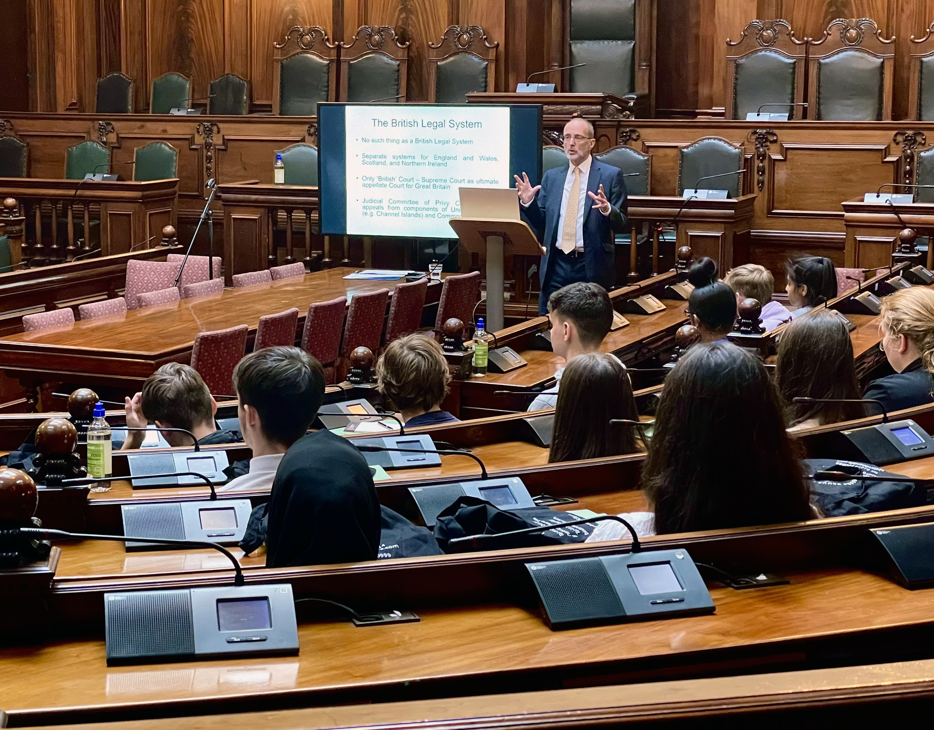 A group of young people in a courtroom watching a man give a presentation at the front