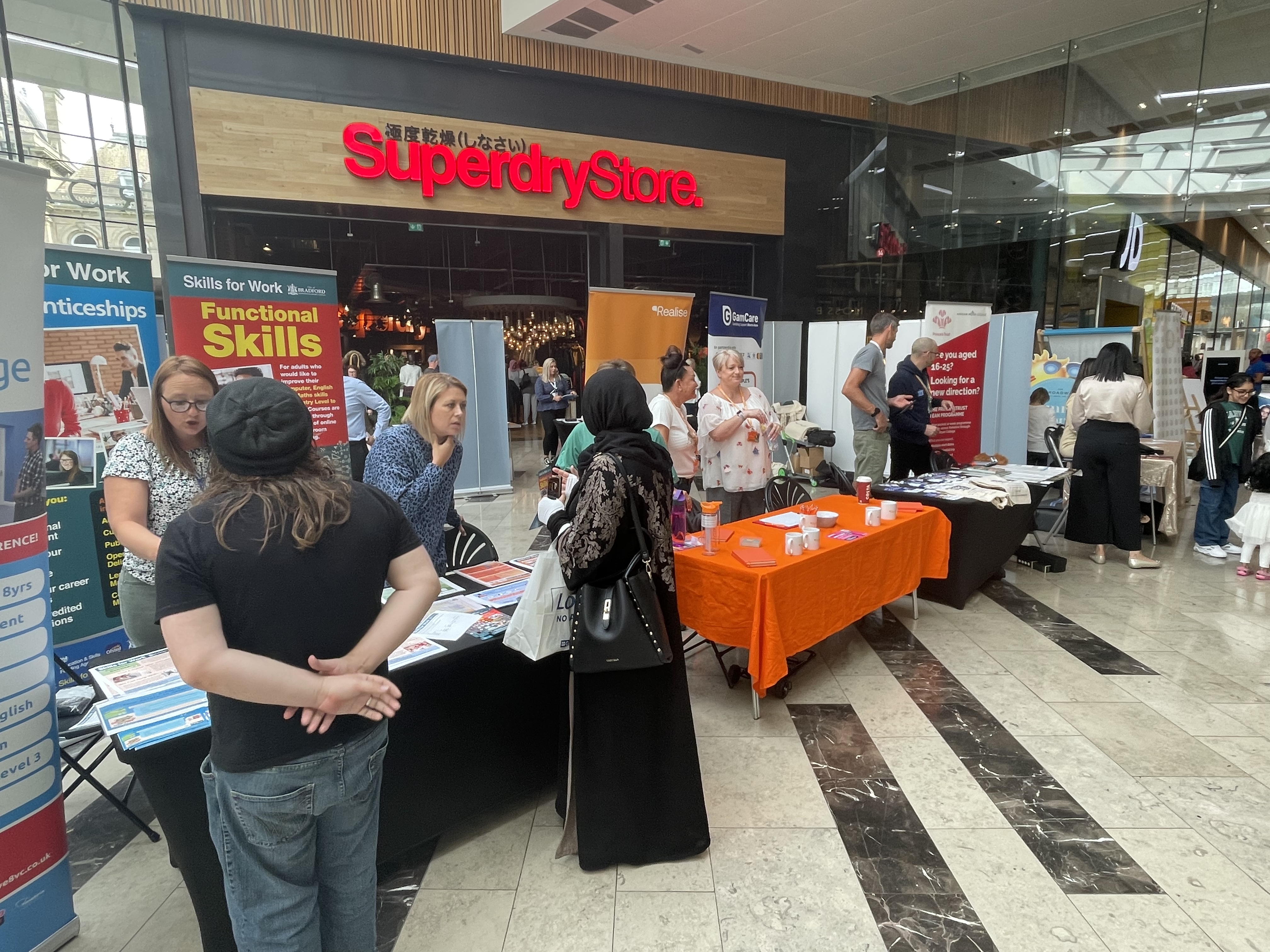 A number of stalls in the Broadway shopping centre with people stood behind 