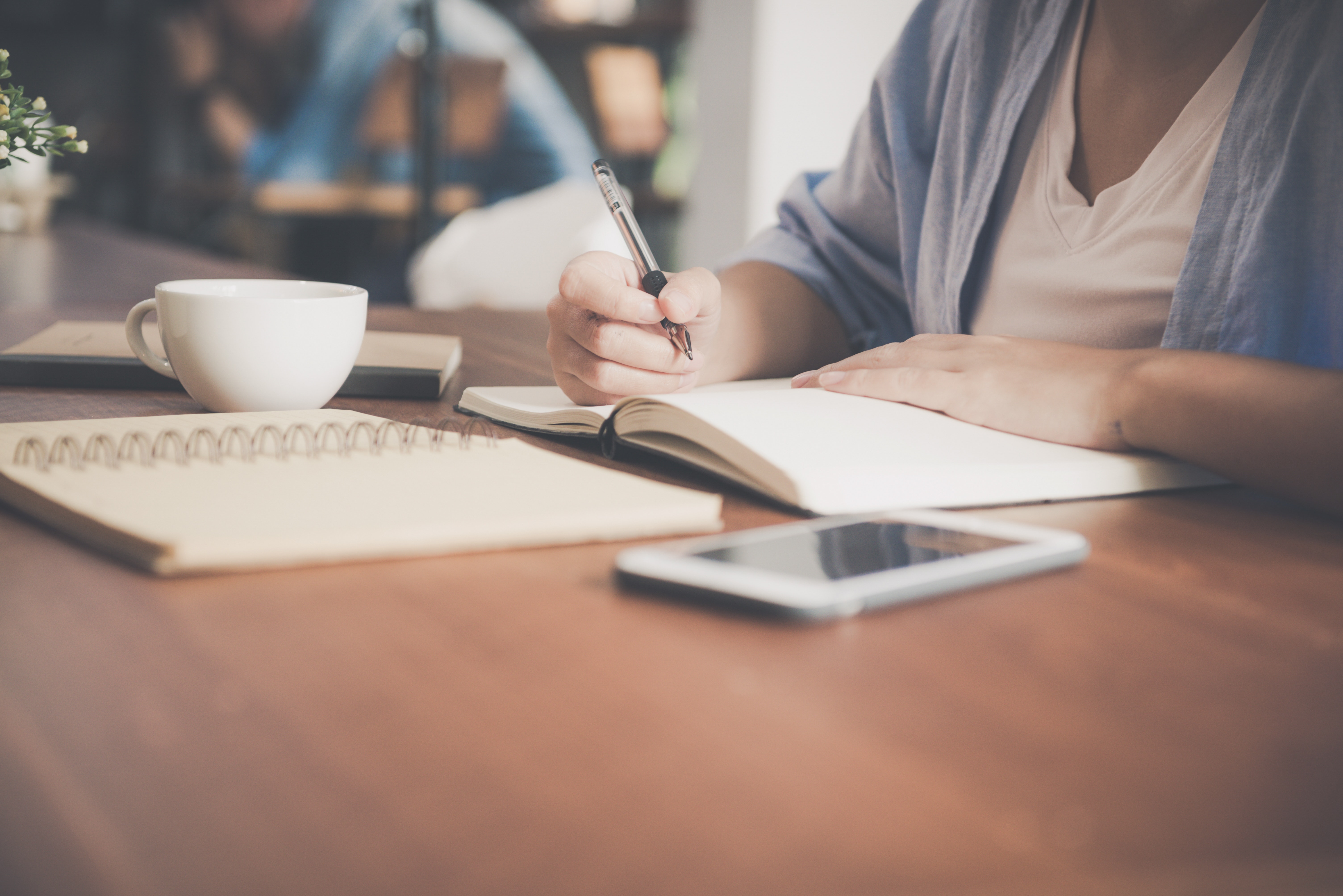 A woman sat at a table writing in a notebook