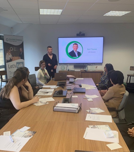 A group of students around a conference table being shown a presentation