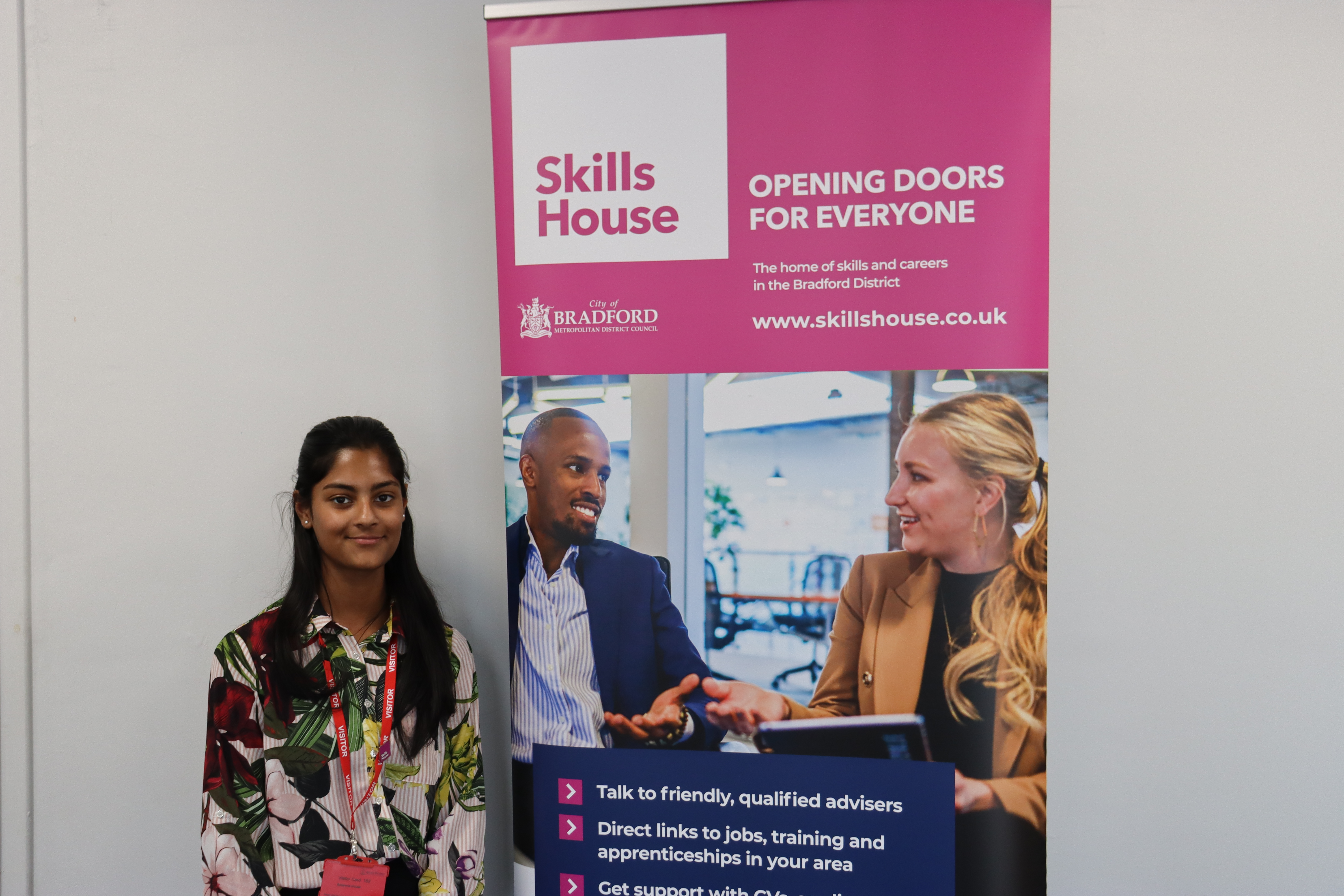 A smiling girl in front of a SkillsHouse banner