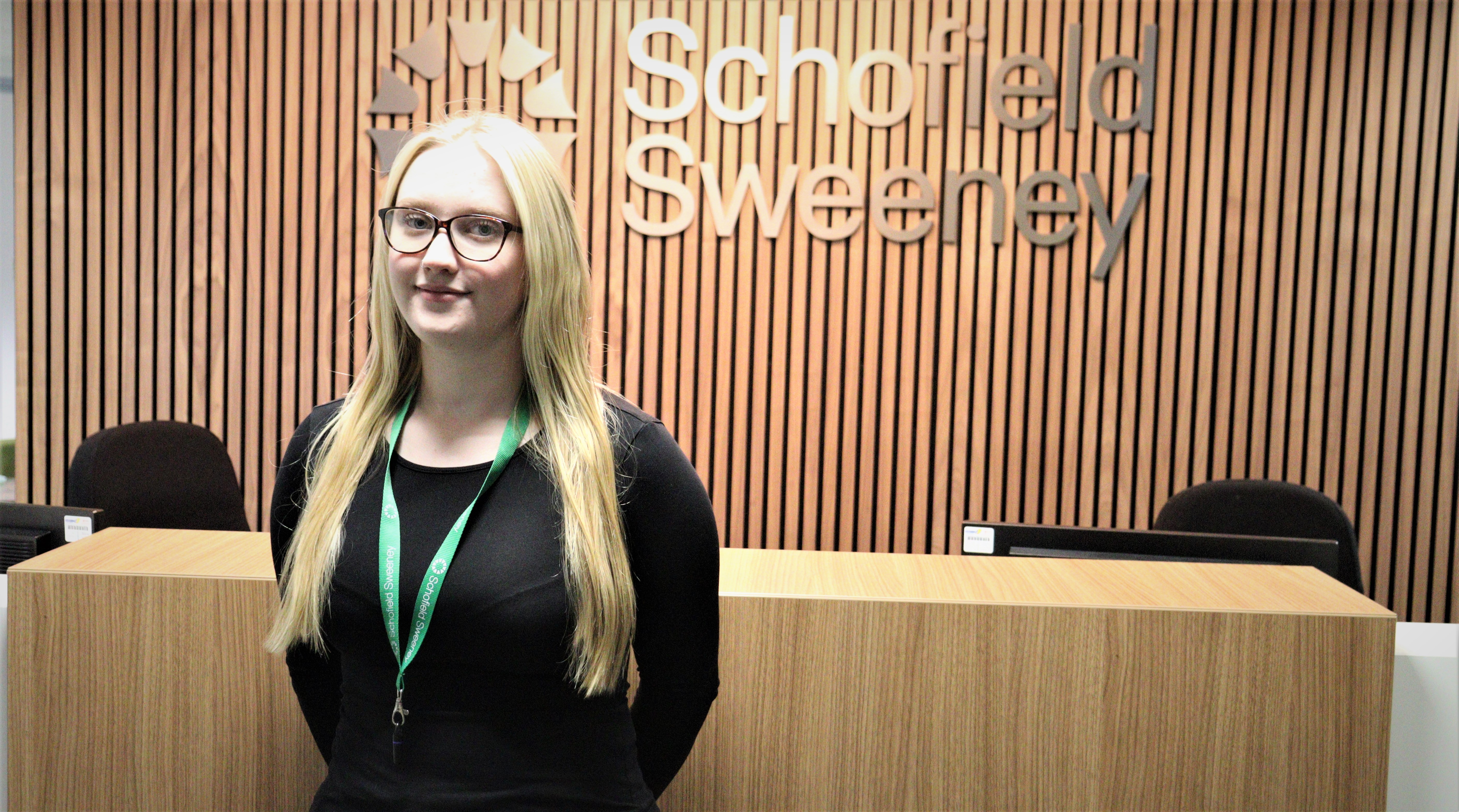 A young woman stood in front of Schofield Sweeney reception desk