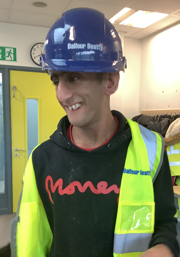 A young man wearing high vis and a hard hat