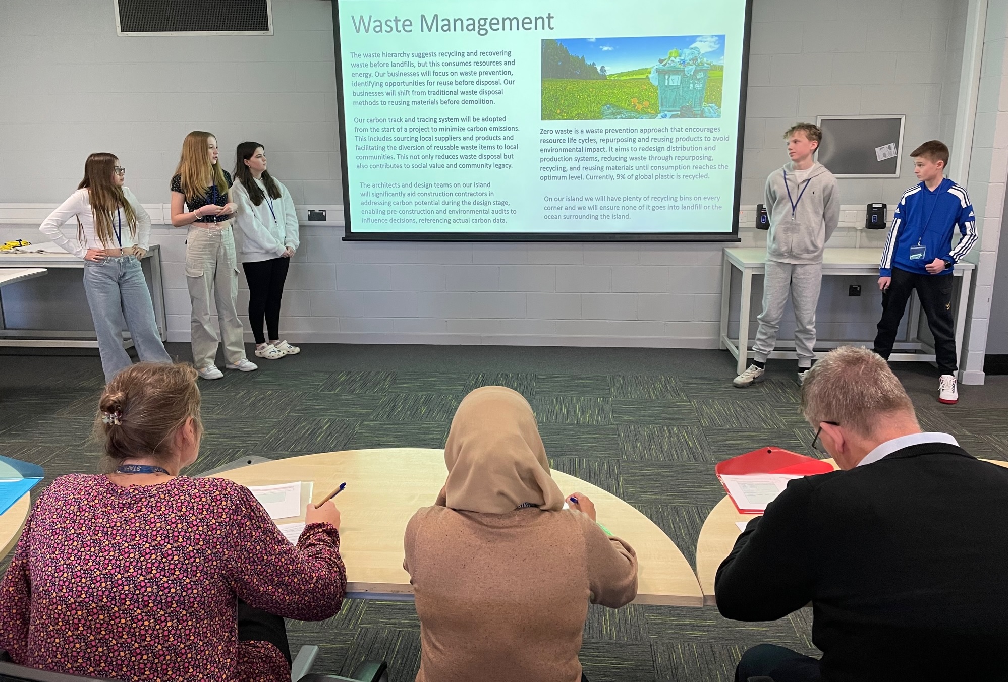 Students showing a presentation in front of three adults
