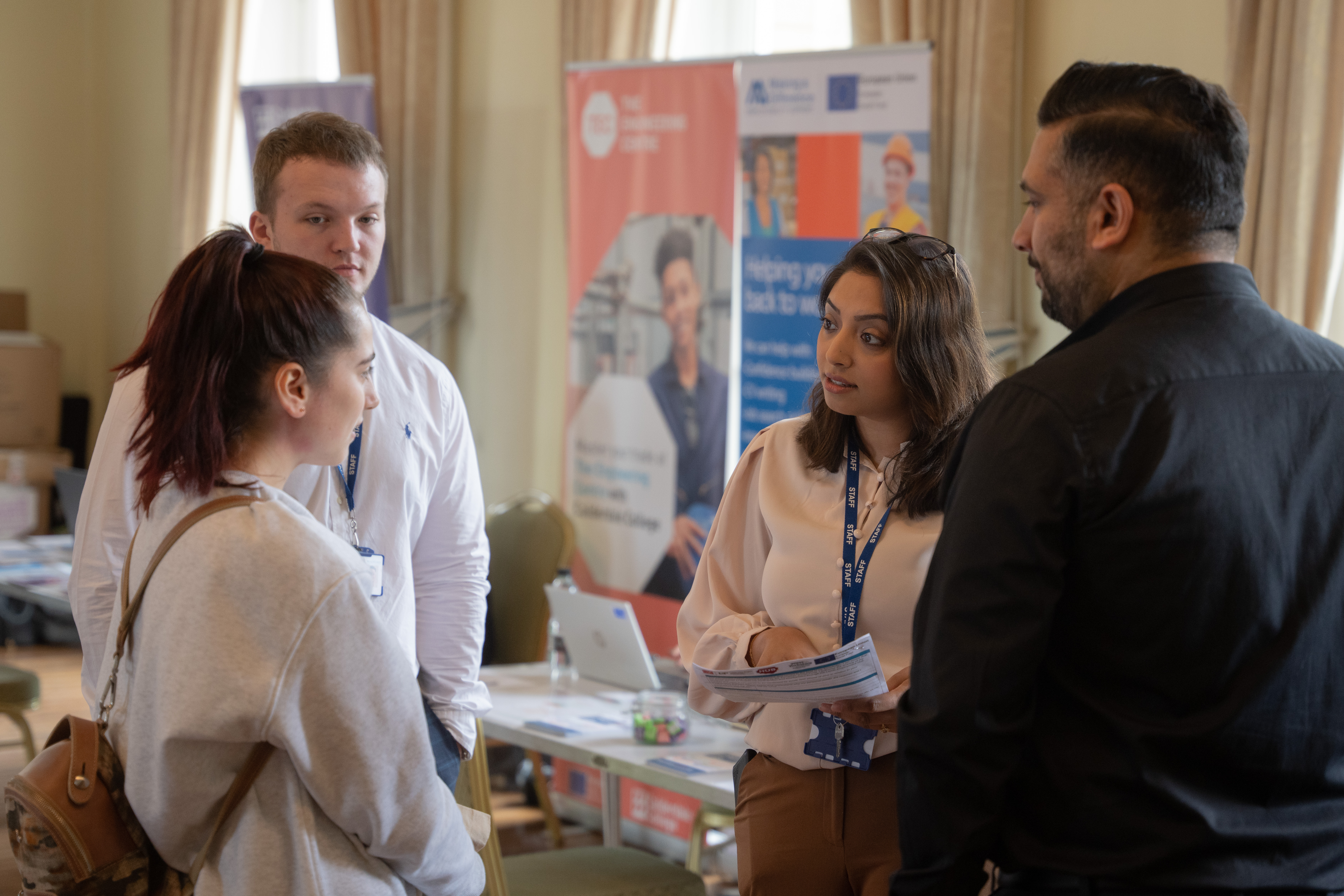 Two people wearing ID badges talking to a third, younger person