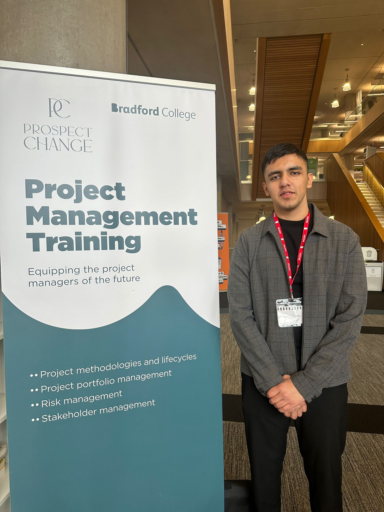 A young man in front of a Bradford College banner