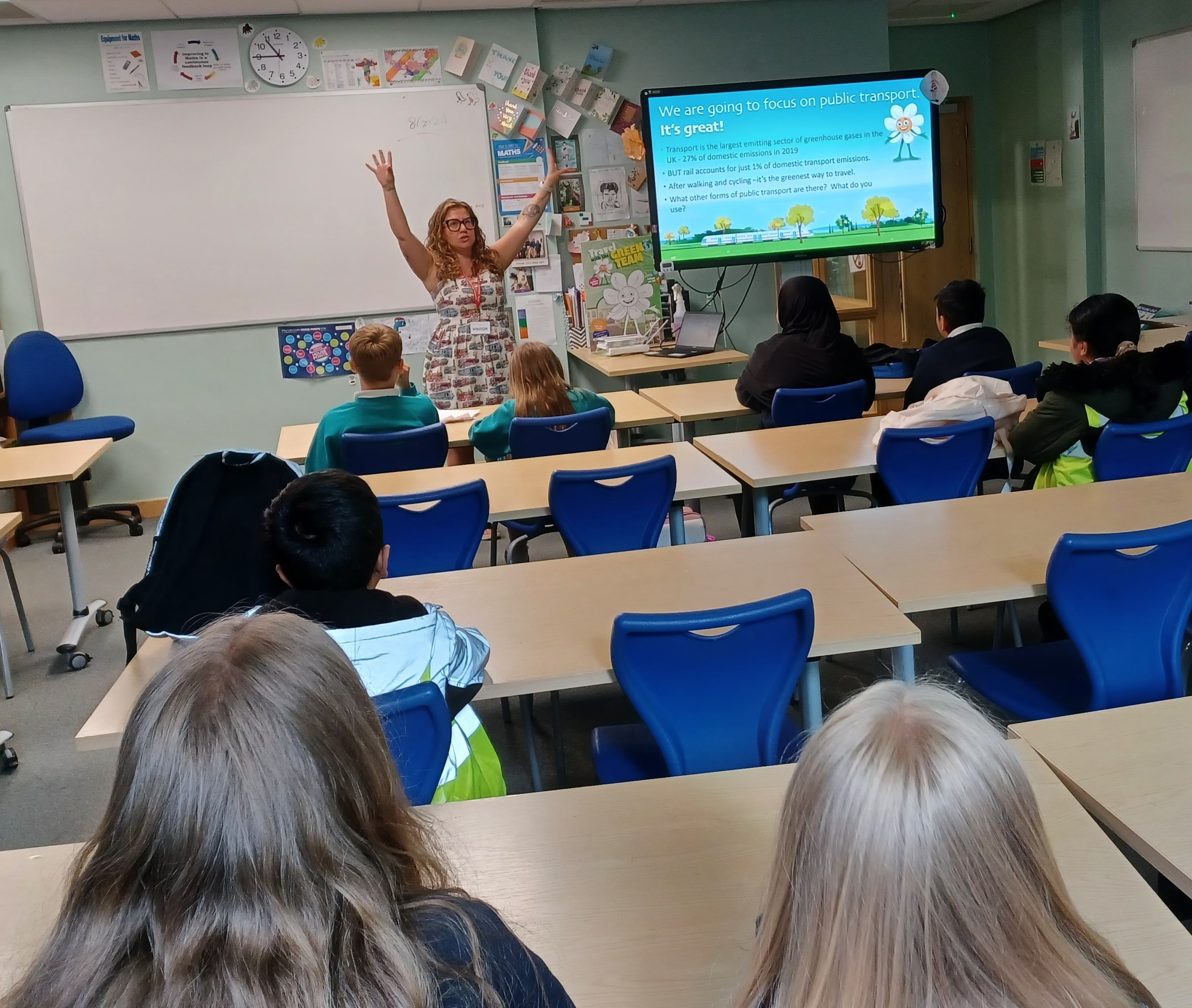 A woman standing at the front of a classroom doing a presentation to schoolchildren